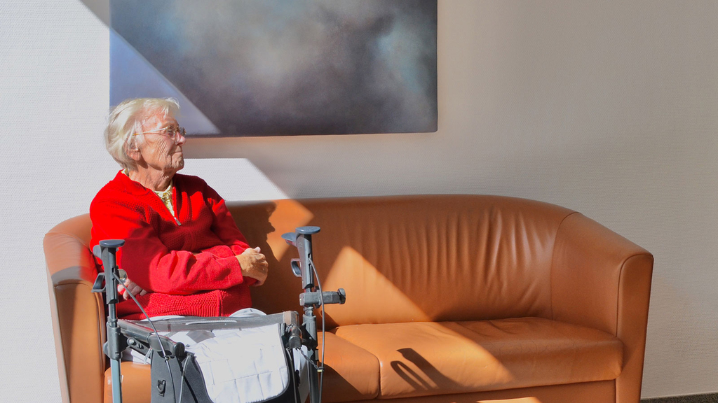 Bewohnerin des Convenio Gelsenkirchen mit Rollator ruht sich auf einem Ledersofa aus