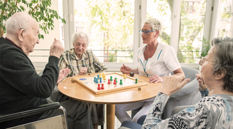 Bewohner und eine Pflegekraft beim gemeinsamen Brettspiel im Convenio Gelsenkirchen