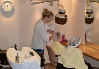 Hauseigener Friseursalon im Convenio Gelsenkirchen: Friseurin legt einer Bewohnerin Lockenwickler ein