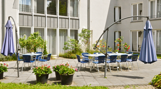 Innenhof-Terrasse des Convenio Gelsenkirchen mit Tischen, Sonnenschirmen und Blumenkübeln